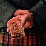 A man in a kilt holding a whisky glass